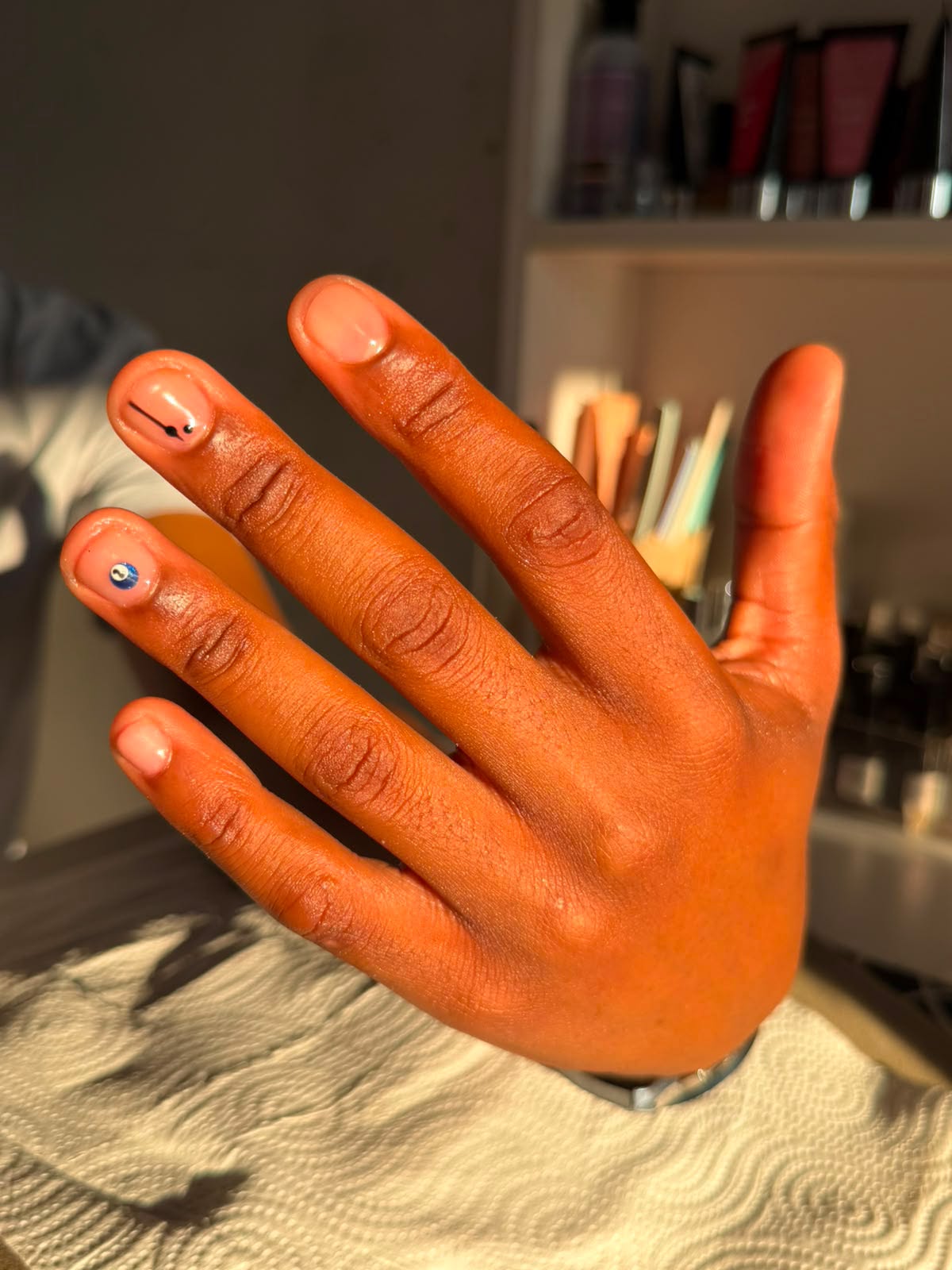 Short natural nails with tiny minimalist line art and a blue accent dot
