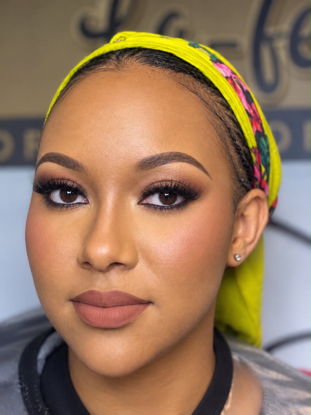 Smoky brown eyes, full lashes and a matte nude lip, with a yellow head wrap