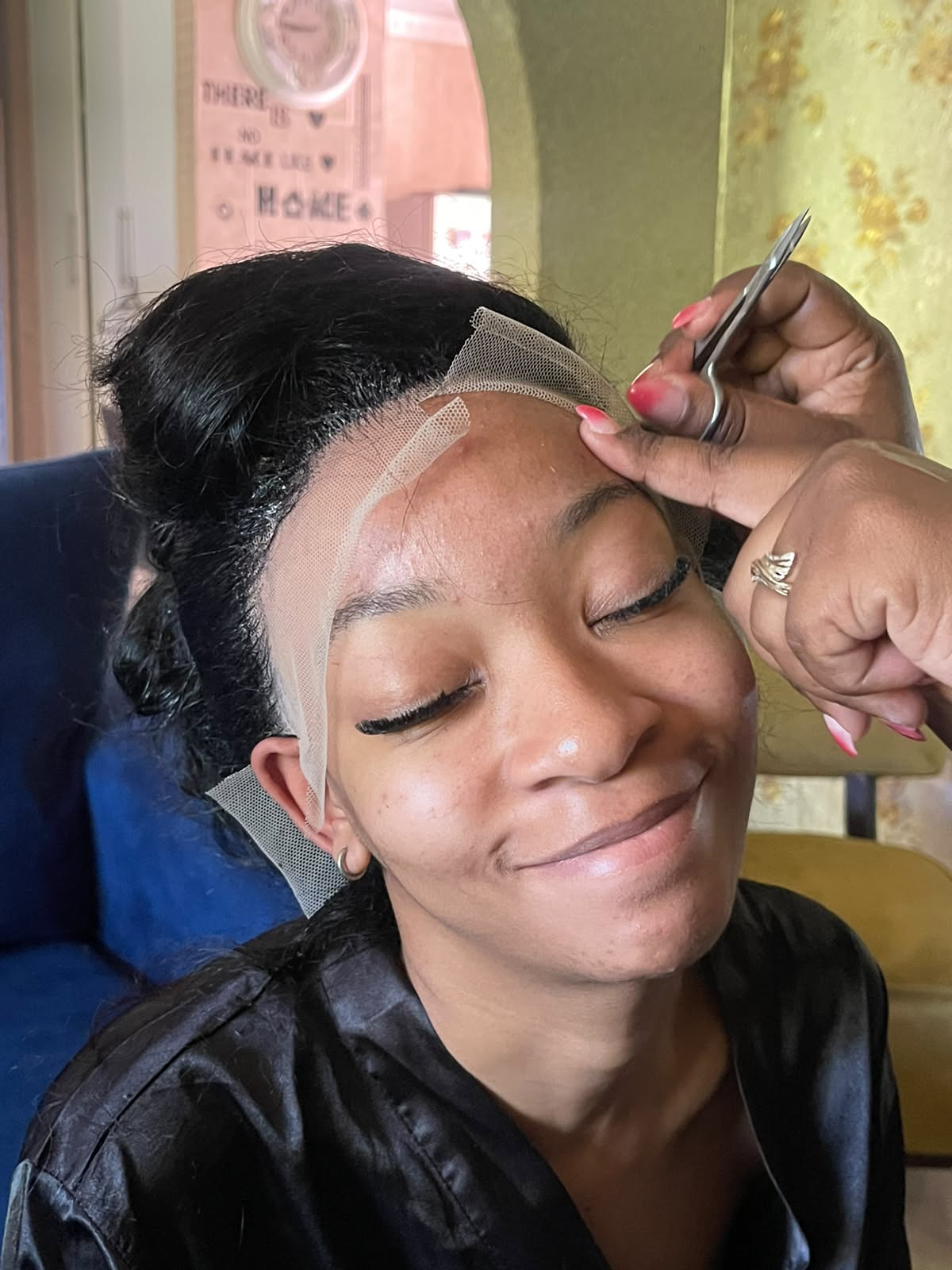 Stylist laying the lace of a wig install, with lashes already applied