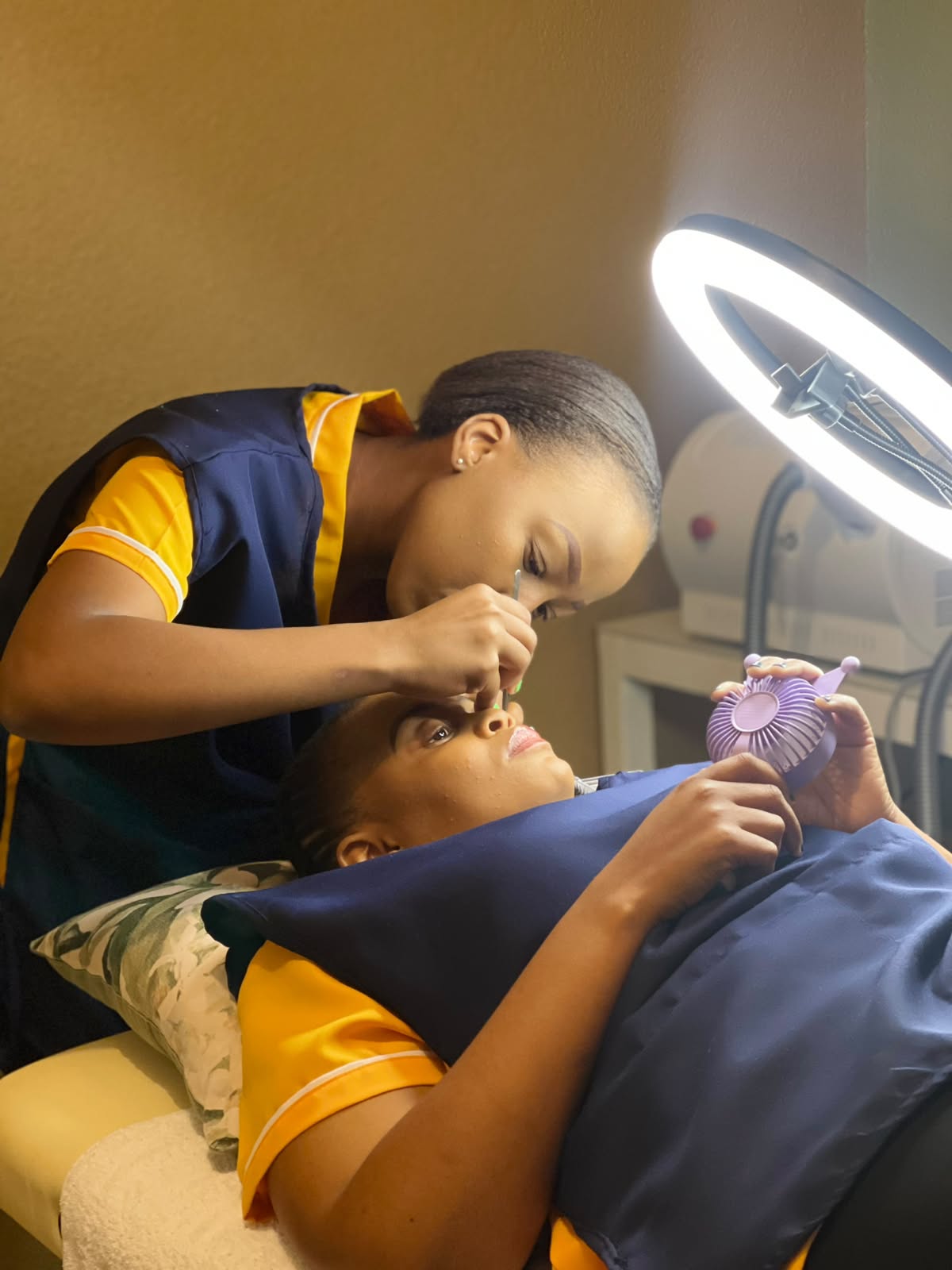 La-fe lash technician applying extensions to a client under a ring light